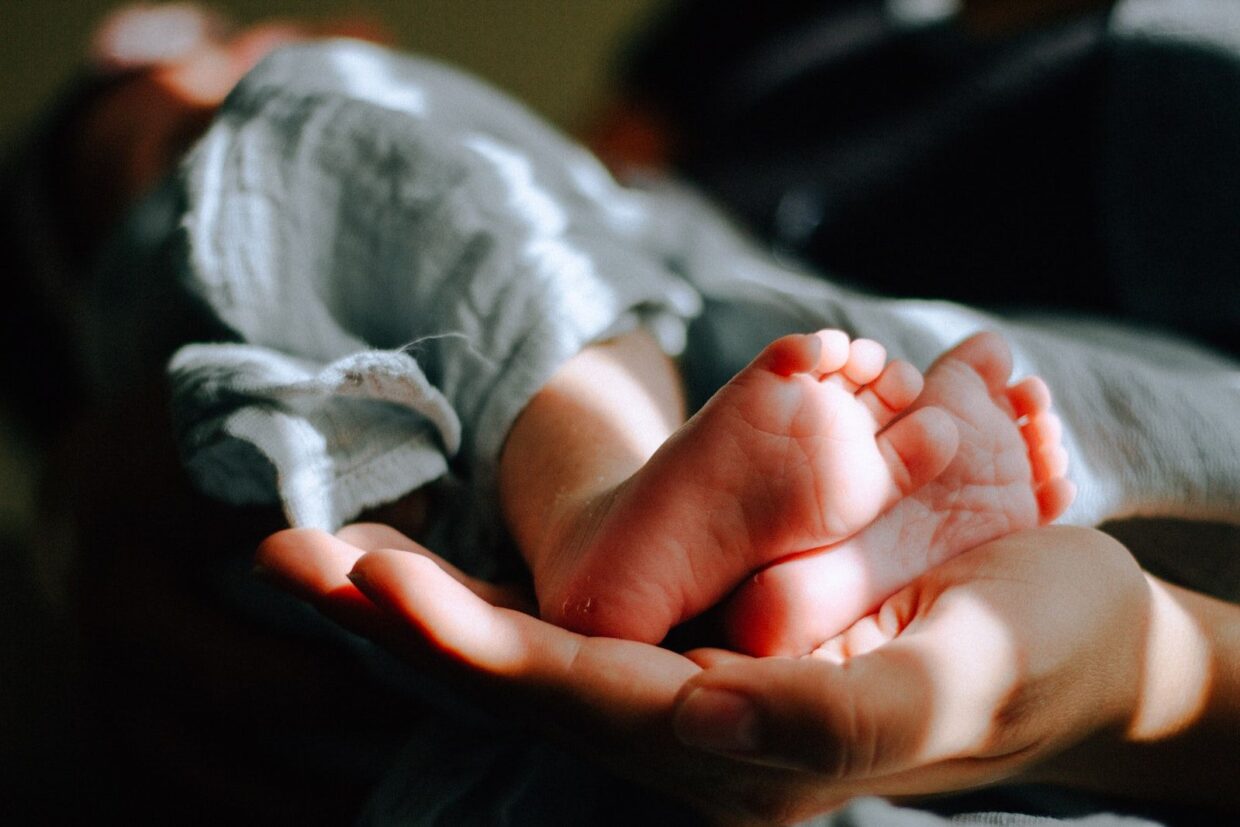 personne portant les pieds d'un bébé dans le creux de sa main